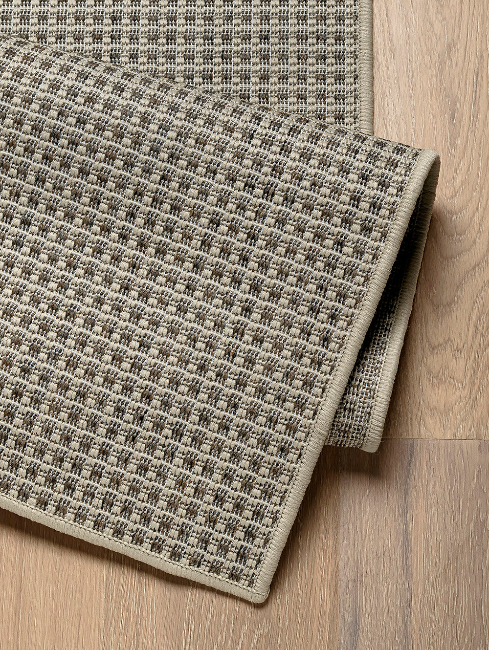 Detalle de alfombra de sisal arena con borde reforzado y textura tejida.