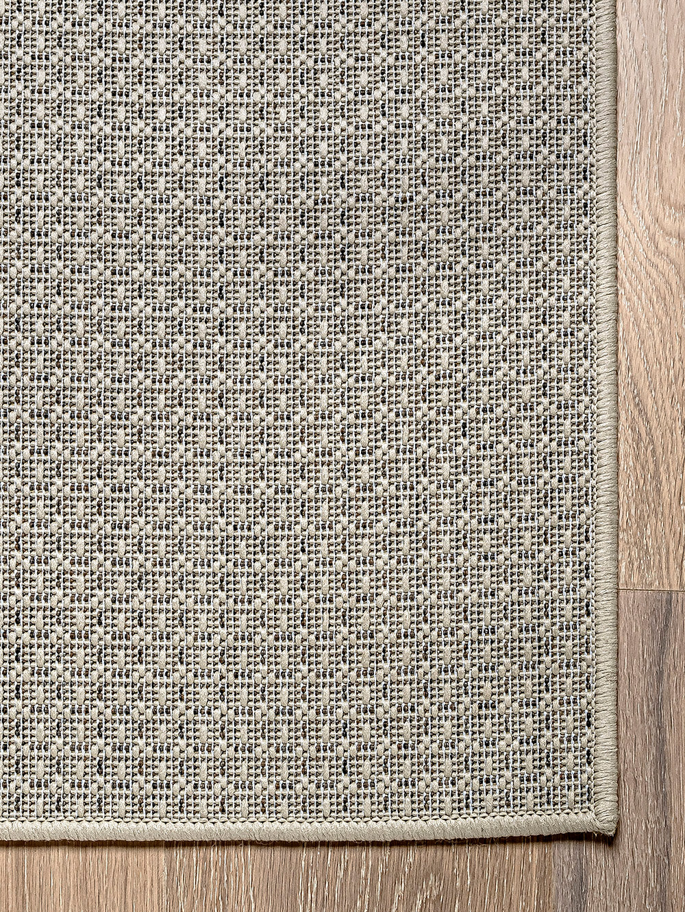 Vista esquina de alfombra de sisal marfil con borde perimetral tejido.