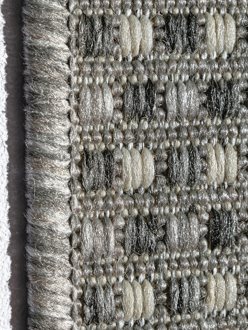 Detalle lateral de alfombra Sisalo Trilenium gris mostrando textura y acabado.