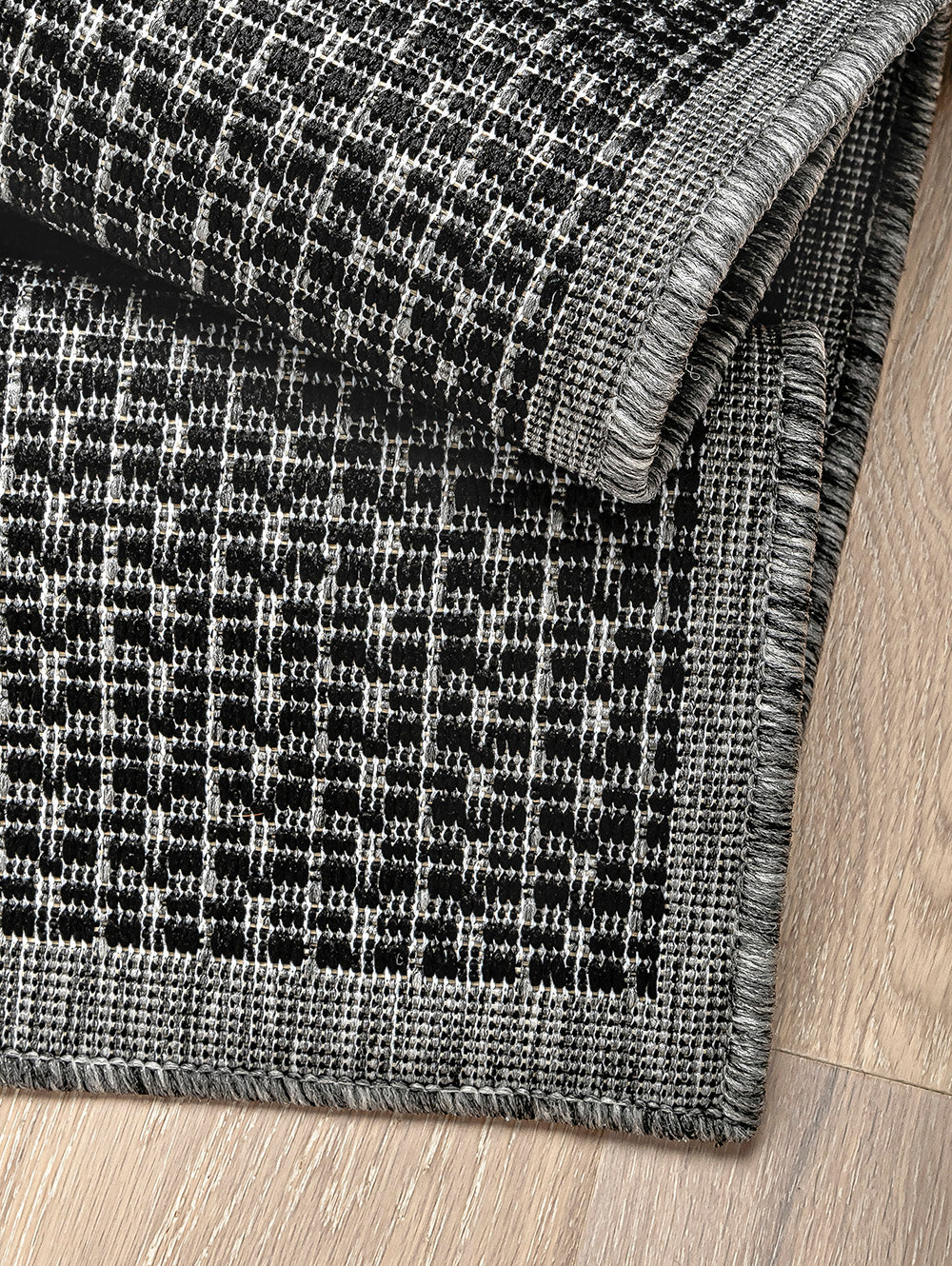 Alfombra de sisal color grafito con detalle de textura y borde tejido.