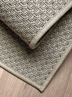 Detalle de dos capas de alfombra de sisal marfil mostrando espesor y terminación.