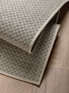 Acercamiento a alfombra de sisal marfil con textura tejida y borde visible.
