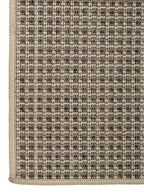 Vista de esquina inferior de alfombra de sisal arena con borde perimetral tejido.