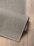 Detalle de alfombra de sisal marfil con borde reforzado y textura natural.