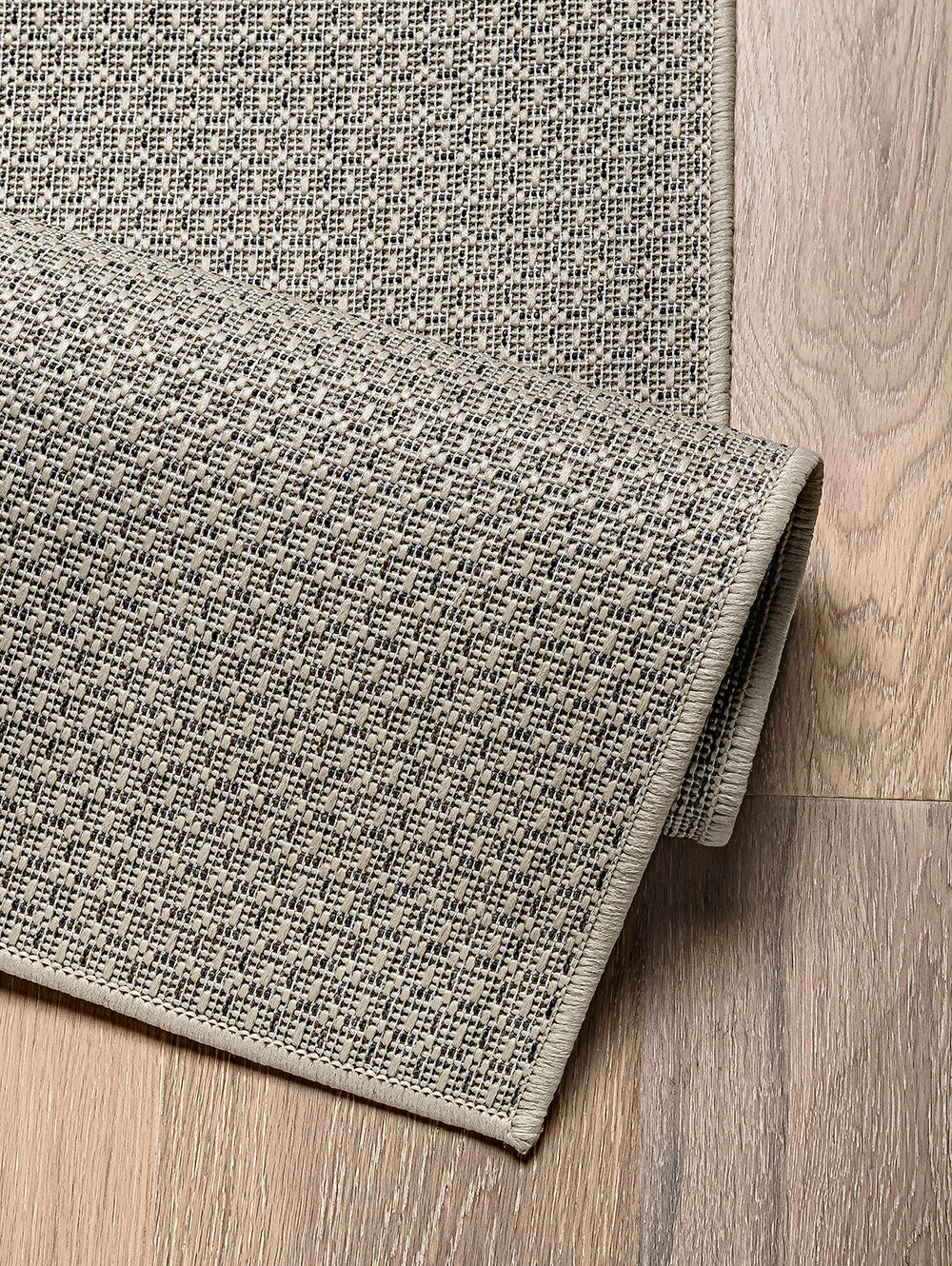 Detalle de alfombra de sisal marfil con borde reforzado y textura natural.