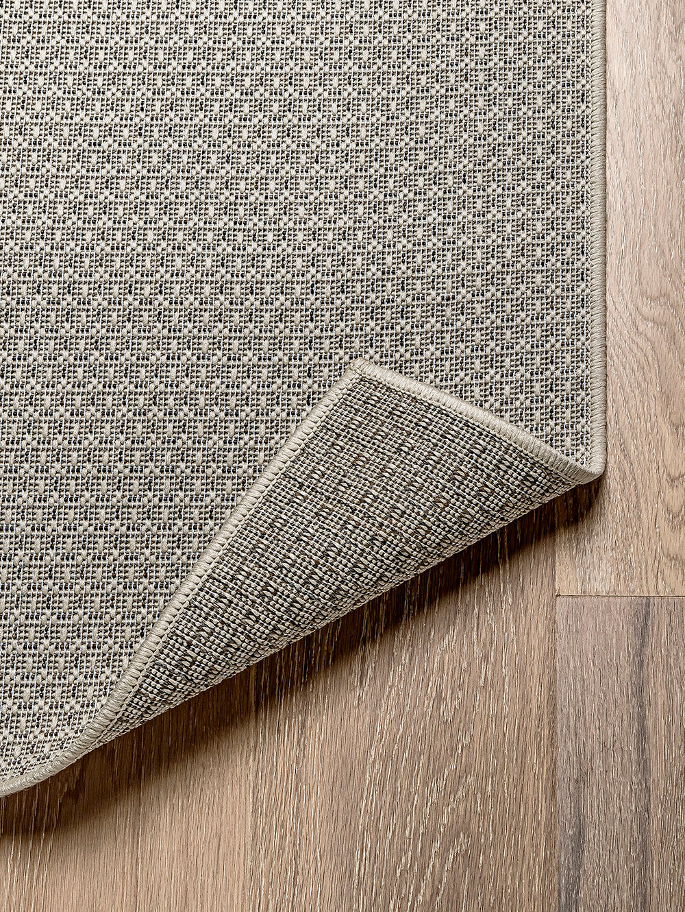 Esquina de alfombra de sisal marfil con detalle de grosor y acabado.