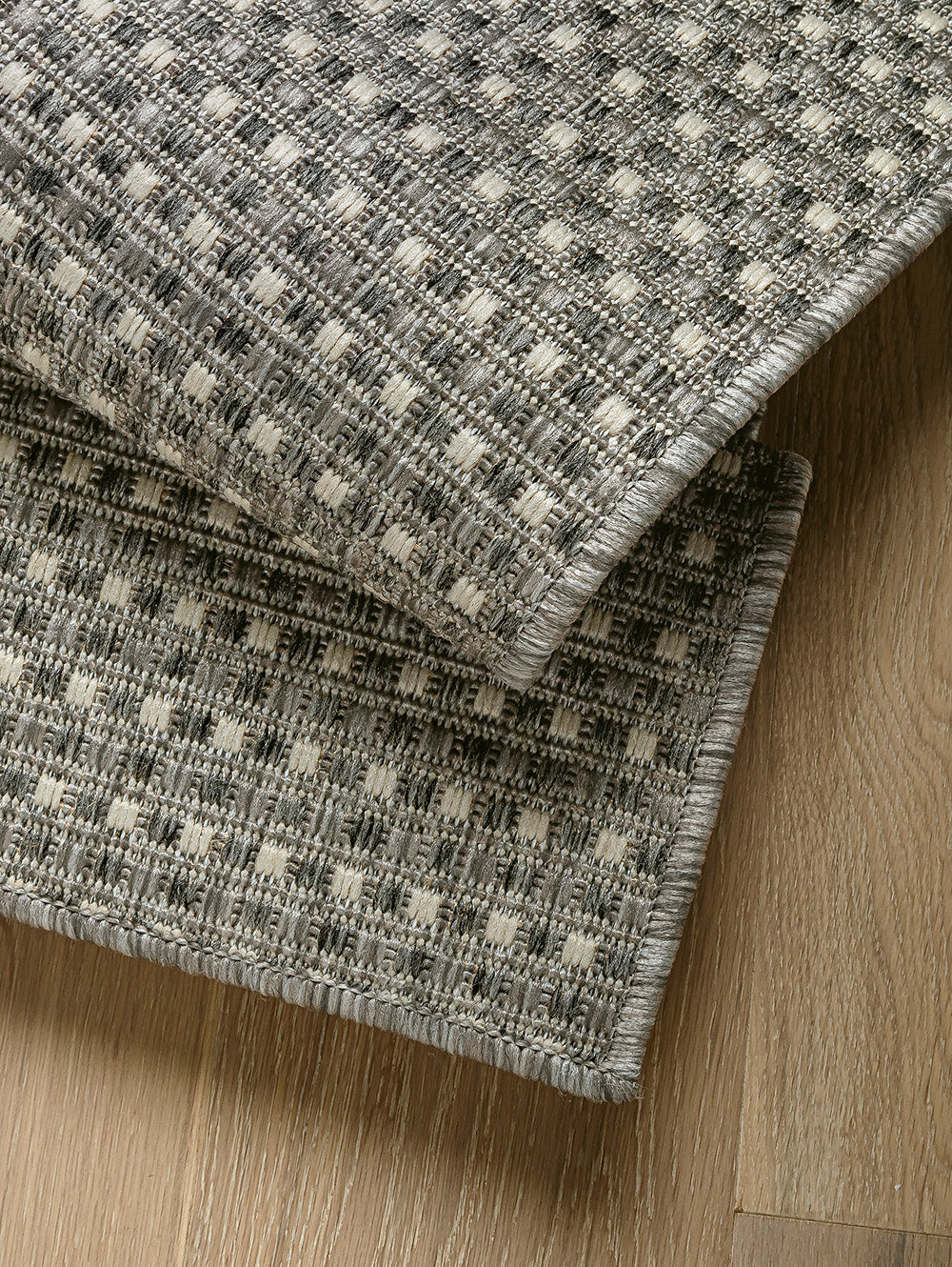 Detalle de alfombra Sisalo Trilenium gris con borde doblado para mostrar espesor.